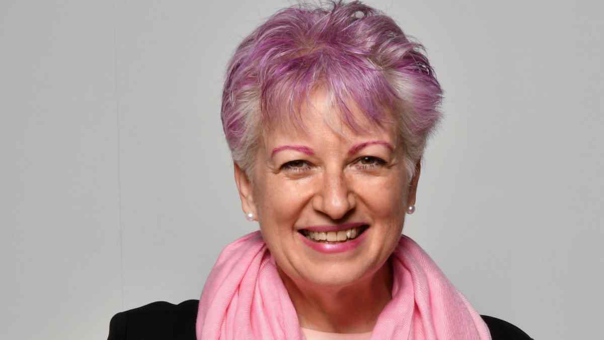 Astrologer Anne Nordhaus-Bike with pink and purple hair, pink scarf